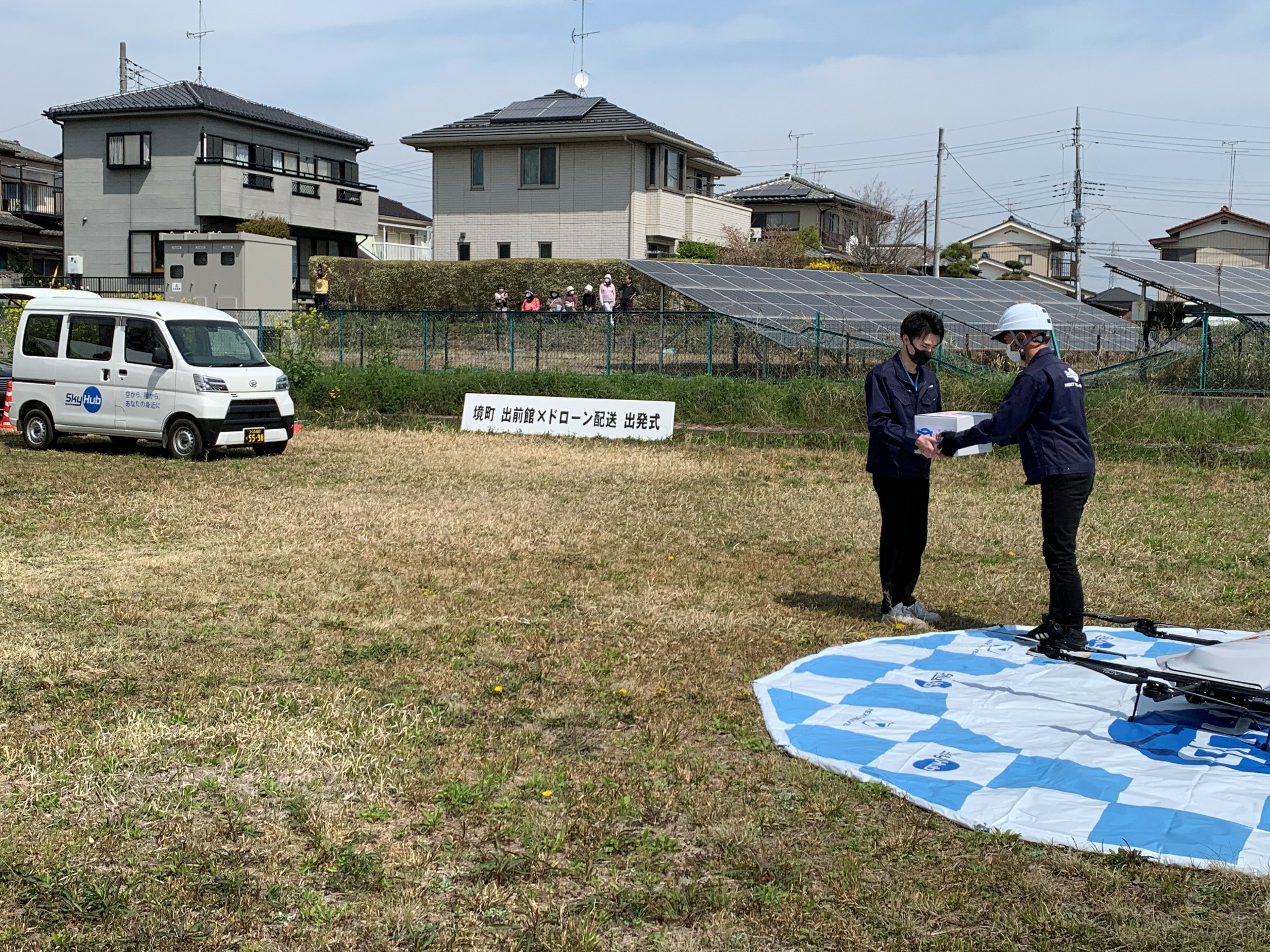 軽バンで運ばれたピザをドローンに積み込み.jpg