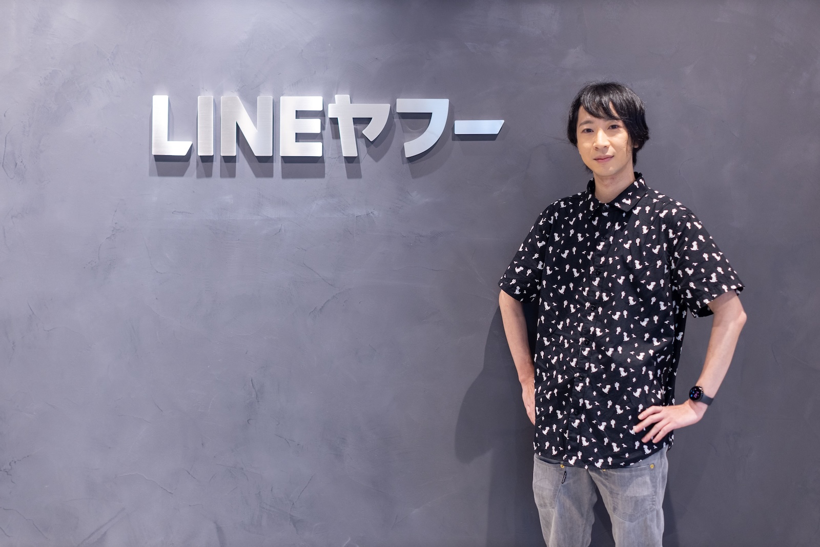 LINEヤフーのロゴ前に立つ男性