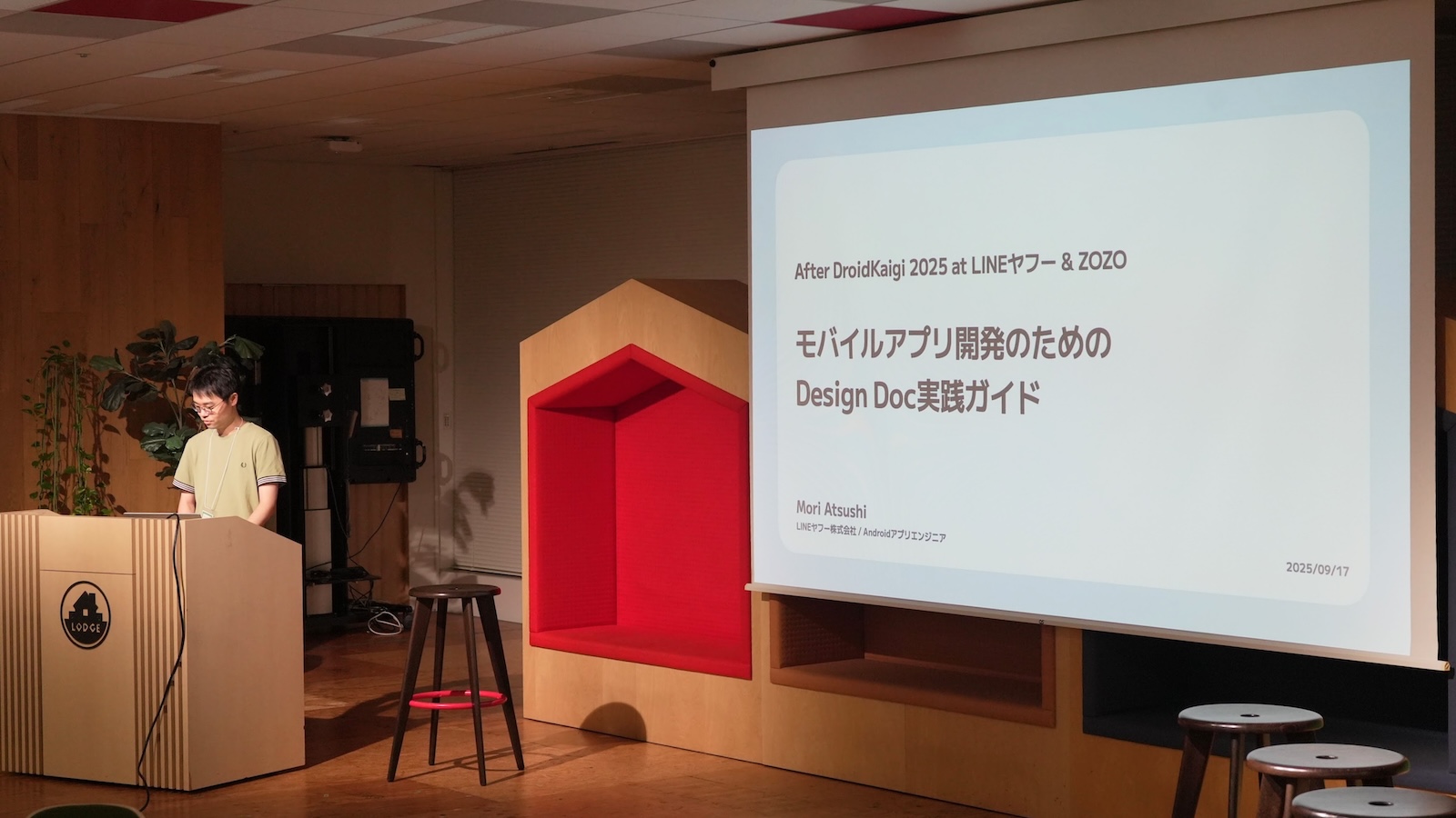 会場の登壇写真。スクリーンに「After DroidKaigi 2025 at LINEヤフー & ZOZO／モバイルアプリ開発のためのDesign Doc実践ガイド」と表示。