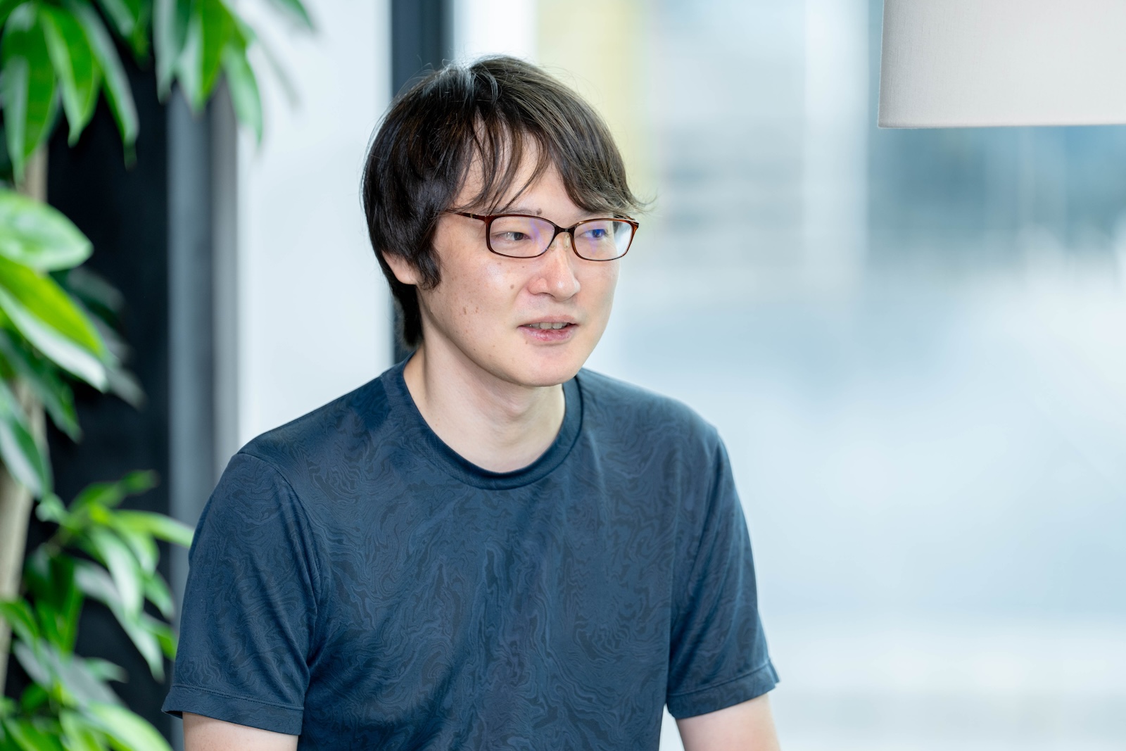窓際の明るい室内で、前を向きながら話す大倉俊平さんの上半身